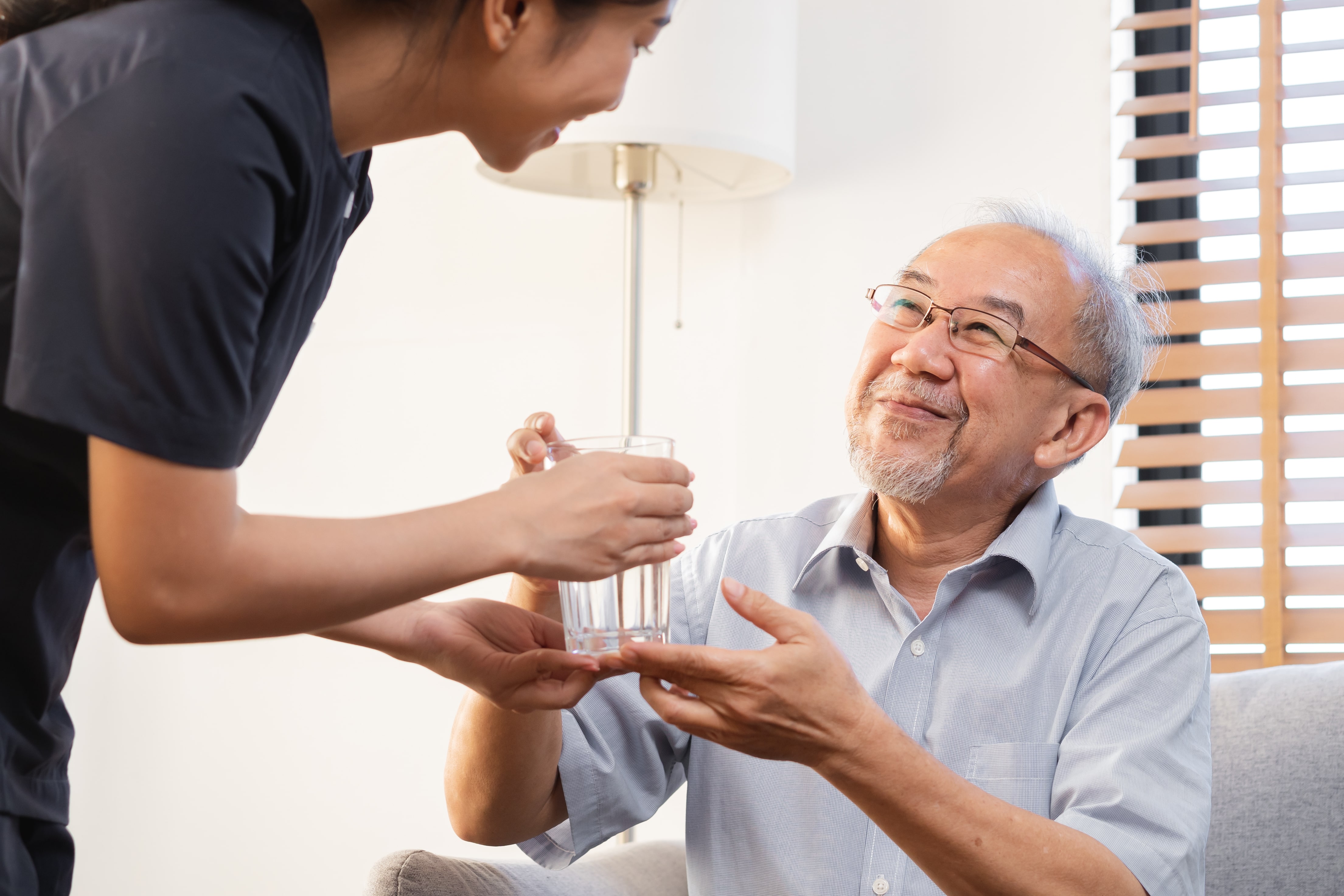 Alzheimer's Care Anaheim A Health Care Aid Handing an Elderly Man a Glass of Water